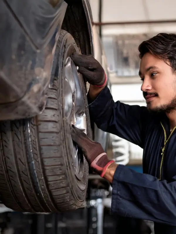 Automotive Technician Checking a Wheel on a Car on a Hoist
