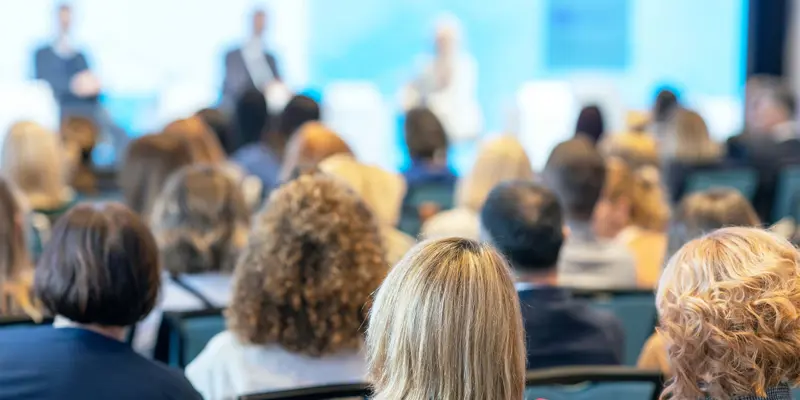 People Looking At A Panel Of Speakers