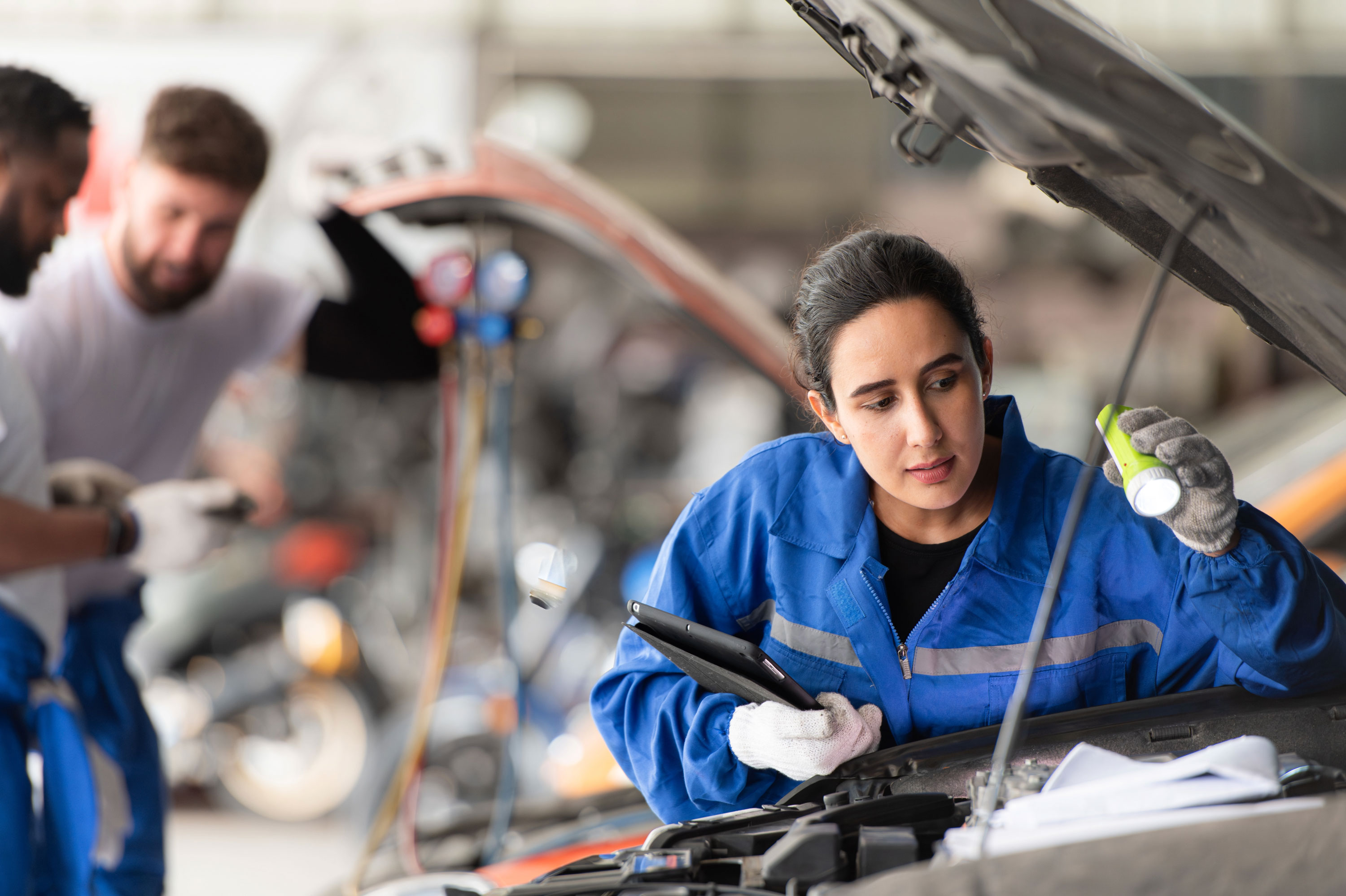 Mechanic inspects vehicle engine with torch