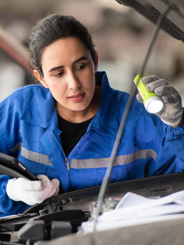Mechanic inspects vehicle engine with torch